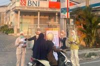 Petugas Bank BNI membagikan bantuan kesehatan kepada warga sekitar.